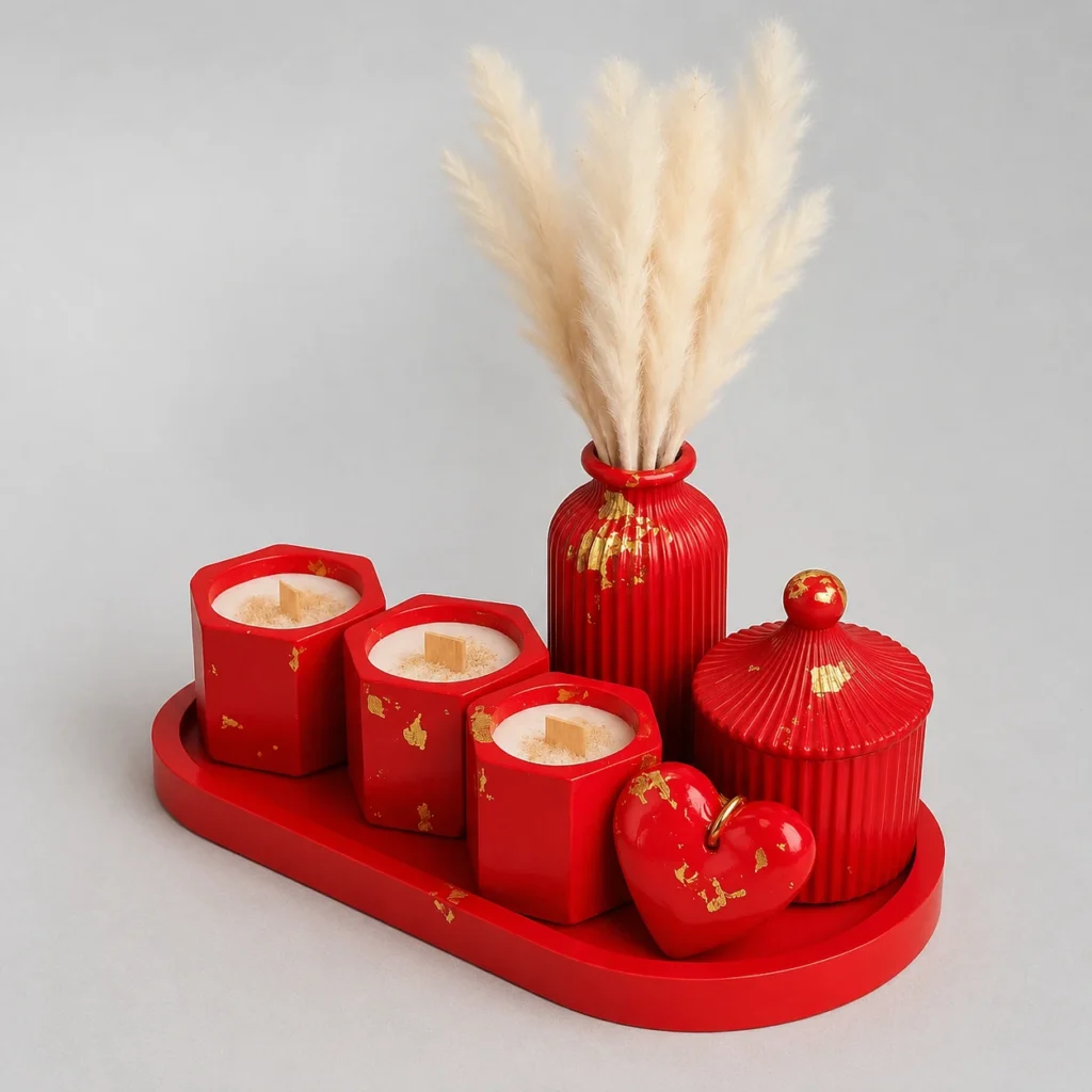 Red decorative tray holding four square candle holders, a tall red vase with fluffy pampas grass, a ribbed lidded jar, and a heart ornament.