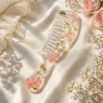 Handmade floral resin hair comb with handle featuring pink flowers and gold flakes on soft satin background