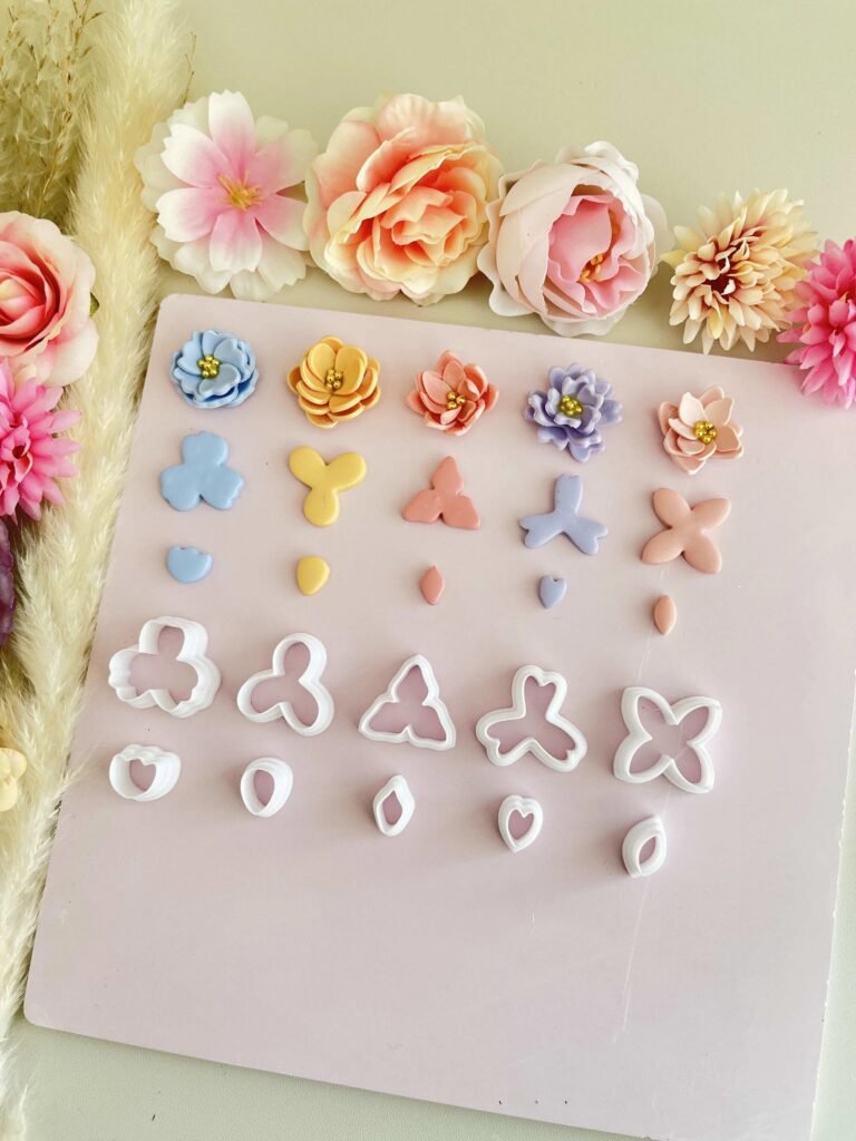 Pastel sugar cookies cut into flower and butterfly shapes on a pink board, with decorative paper flowers along the top edge.