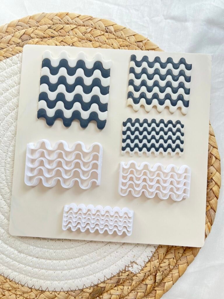 Assorted white and navy wavy silicone molds placed on a cream board atop a woven mat.