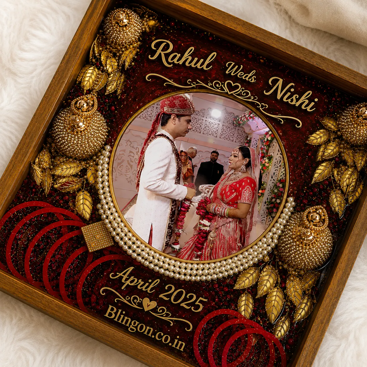 Circular photo frame with a bride and groom in traditional Indian attire, surrounded by gold embellishments and jewelry; reads 'Rahul Weds Nishi' and 'April 2025'.