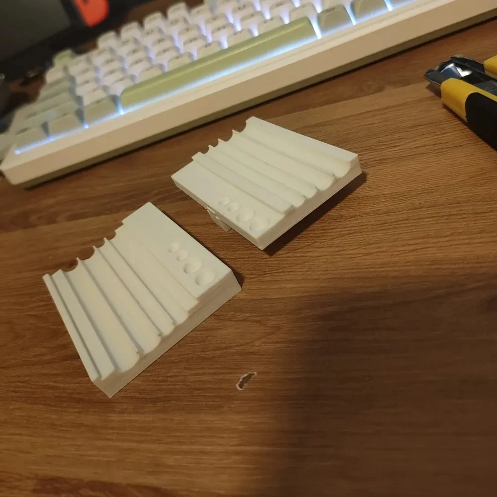 Two white plastic bricks with ridged, ribbed tops on a wooden desk, with a keyboard in the background.